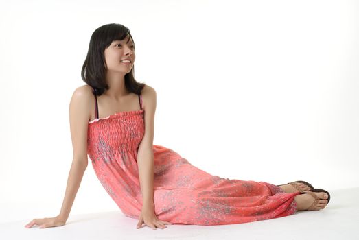 Young girl on pink dress sit, isolated on white.