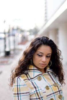 A pretty Indian woman with curly brown hair posing outdoors.