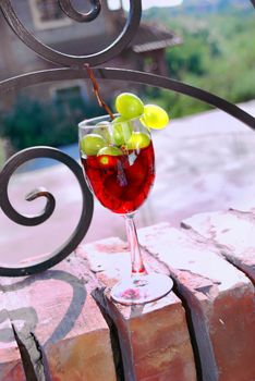 Red wine glass with grape over brick fence