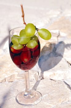 Red wine glass with grape over stone background