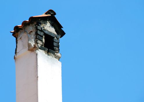 Old smoky chimney isolated over blue sky
