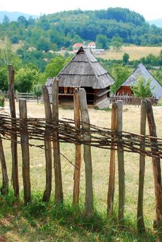 Ethnic Serbia, wooden house behind fence over rural landscape