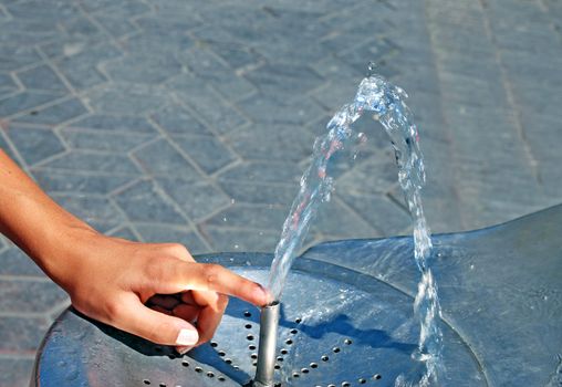 Water drinking fountain with human hand close up