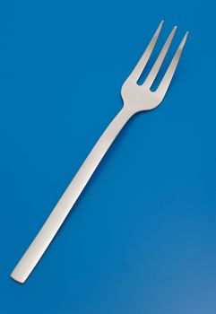 Fork for meat carving isolated on the blue background.