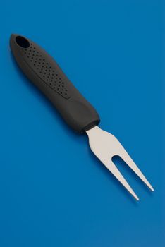 Small barbecue carving fork isolated on the blue background.