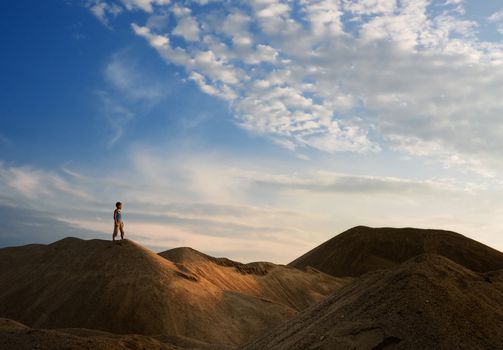 young man go up in sand desert in sundown silhouette