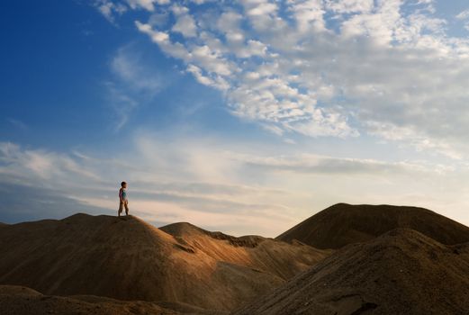 young man go up in sand desert in sundown silhouette