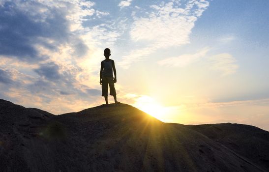 young man go up in sand desert in sundown silhouette