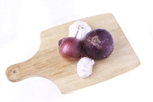 A selection of vegetables of root foods on a cutting board ready for cutting isolated on a white background