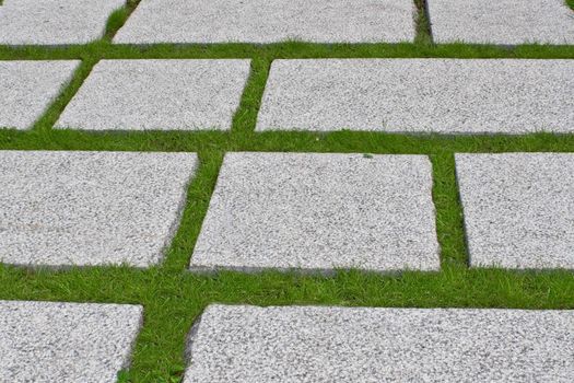 Path from the granite plates which have been laid out on a green grass