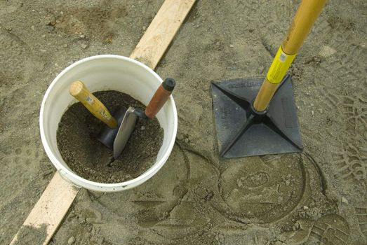 looking down on plastic bucket with hammer, spade, and tamper