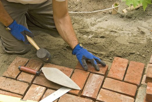 tight shot of man's hands laying brick patio