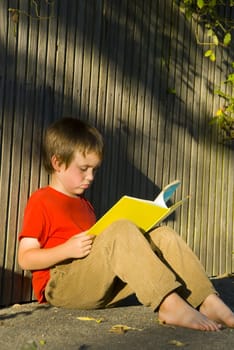 bare foot  boy in red t-shirt a reading book