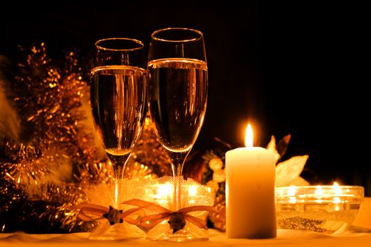 two glasses of champagne, candles with christmas decorations