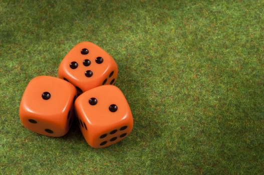 Three orange dice over a red and green carpet