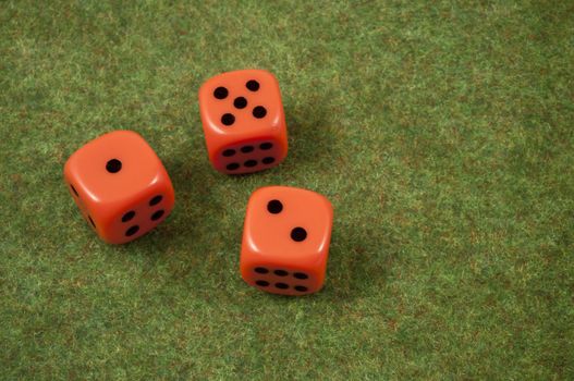 Three orange dice over a red and green carpet