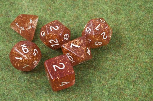 Full set of orange dice over a green carpet