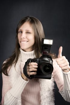 Pretty photographer with a professional camera and flash gives Thumbs Up