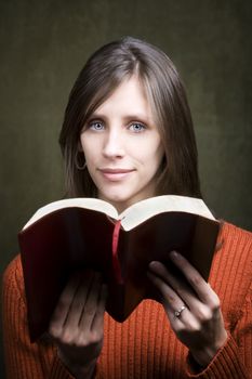 Pretty woman in orange sweater with Bible