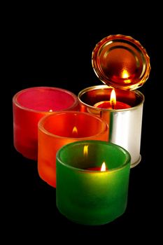 red candle on a tin can over black background