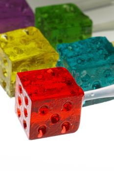 bounch of colorfull translucent dice shaped lollipops backlit on white background