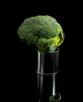 fresh vivid green broccoli on a tin can over black background