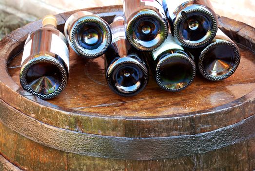 bottles of wine lying over wooden barrel