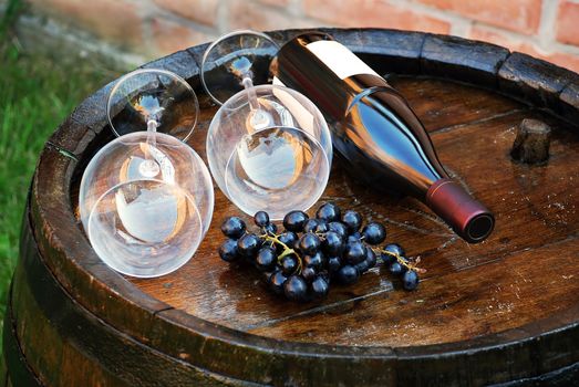 glasses and bottle of wine lying over wooden barrel