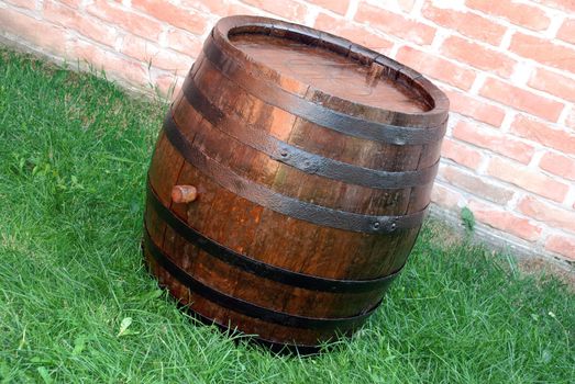 old  wooden wine brown barrel over grass and brick wall