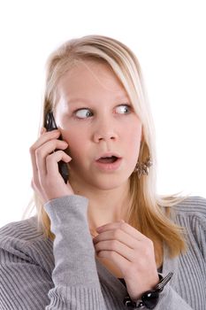 Young blond girl on the phone looking shocked