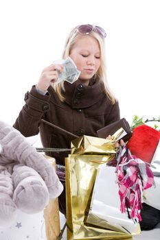 Cute blond girl sitting on the floor with her shopping bags and counting money