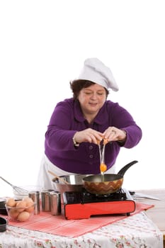 Female chef breaking an egg above her pan