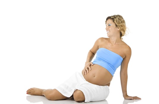 Beautiful pregnant woman seated on the floor and isolated on white background 
