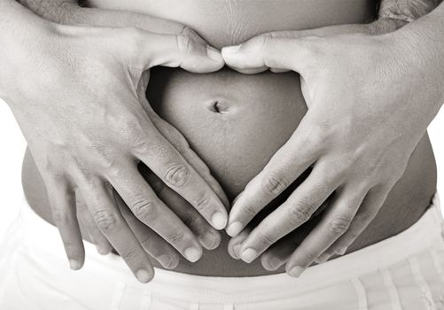 Pregnant women wrap her arms around the belly in the form of the heart. Isolated on white. 