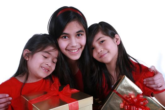 Three sisters wearing red shirts holding presents