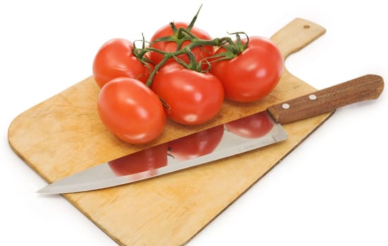 Knife and branch of tomatoes on a chopping board