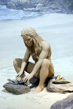 Prehistoric homosapiens sculpture in Hongkong museum. Male using simple tools and preparing fish.