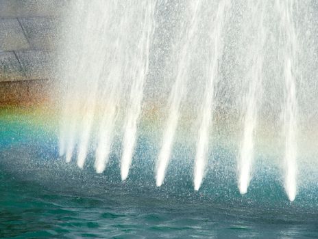 water white streams in blue fountain with rainbow