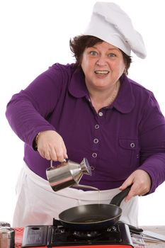 Female chef pouring oil in the pan looking funny