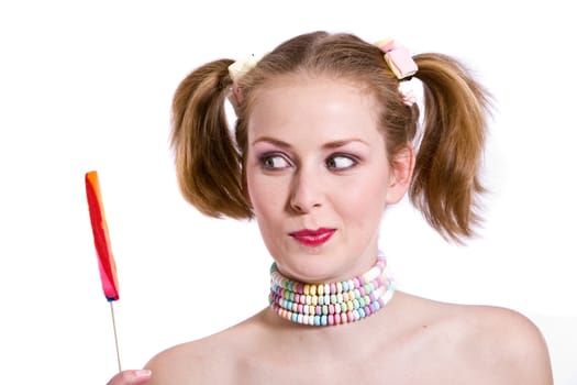 Cute young girl with two ponytails looking at a candy stick