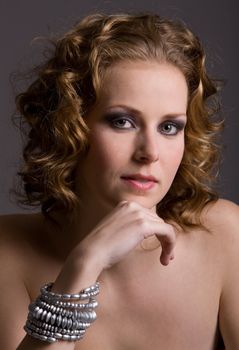 Beautiful young woman with curls in thoughtful pose