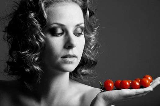 Beautiful girl in black and white holding bright red tomatoes