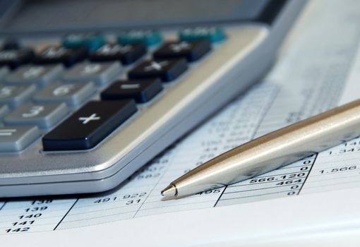 silver calculator with pen and calculations numbers on paper