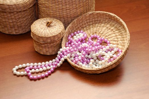 white and pink pearls on basket cover over wooden background