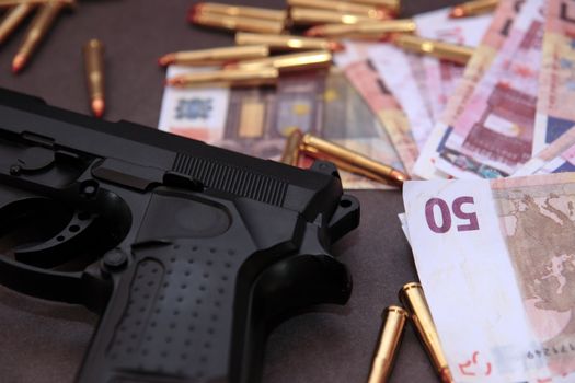 a stash of drugs gun and money showing a dangerous cost to life against a dark background