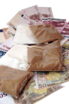 a stash of drugs and money showing a high cost to life against a white background