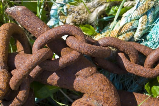 closeup of a rusty chain with a rope in the background