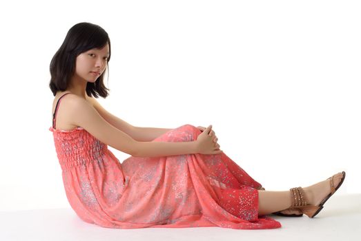 Oriental woman sit on white ground in pink dress.