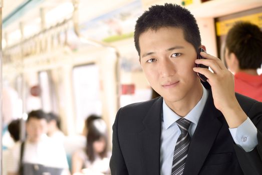 Portrait of young businessman use cellphone in train.