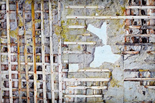 Wooden planks sticking out of the damaged old concrete wall